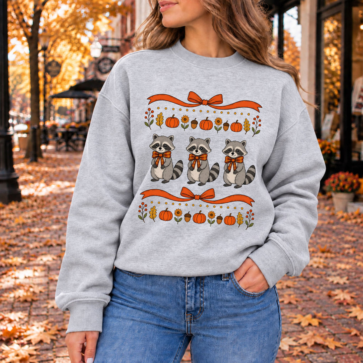 Light gray crewneck sweatshirt with fall raccoon bow graphic and pumpkins