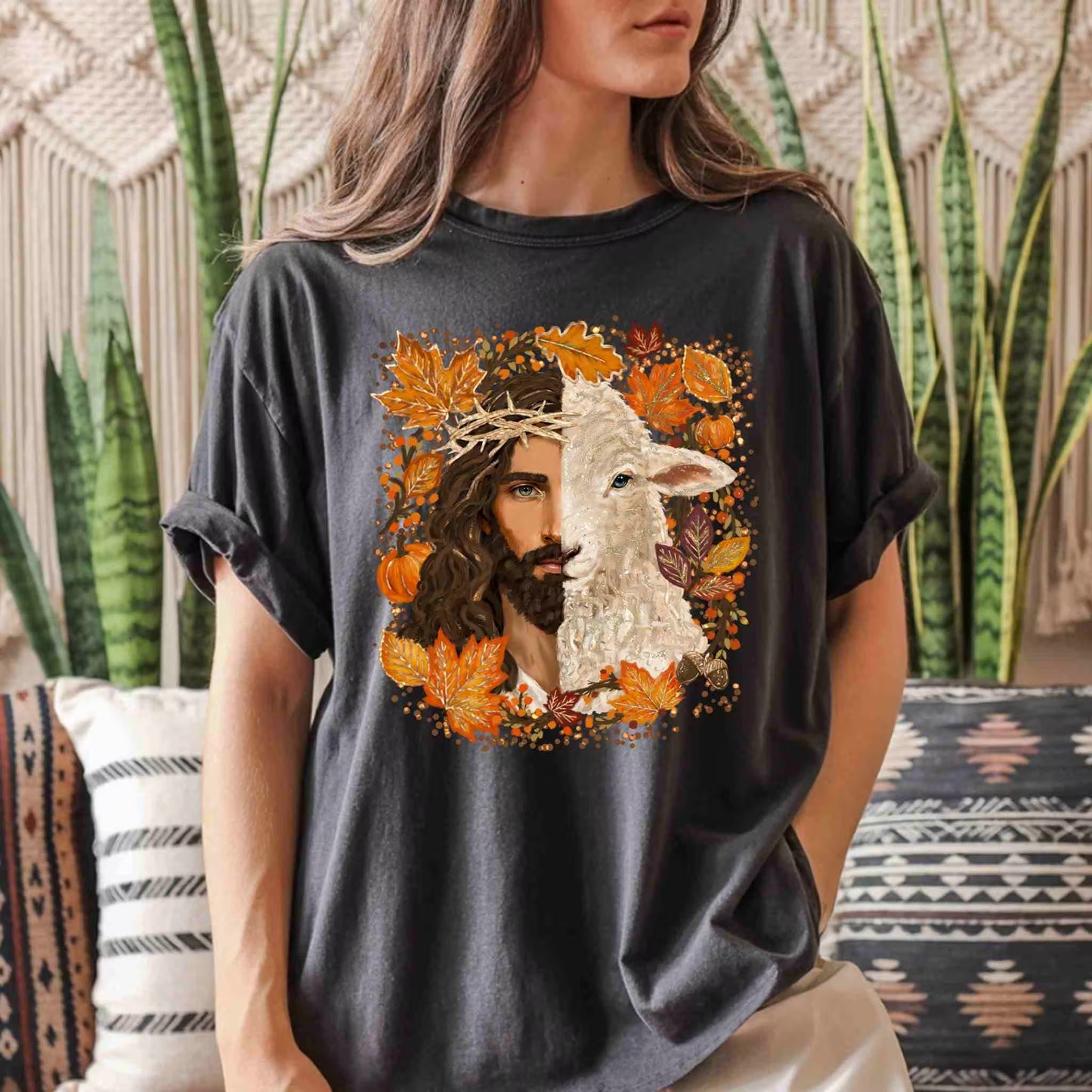 Person wearing a black t-shirt with a graphic design of a man and a lamb surrounded by autumn leaves.