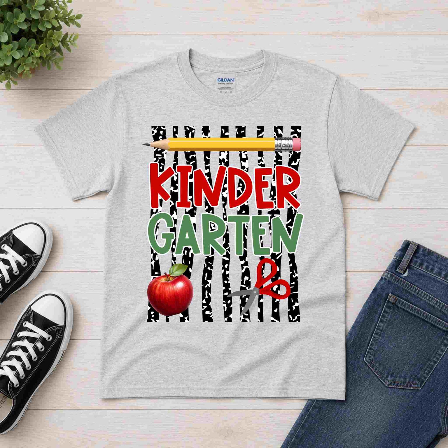 Gray t-shirt with 'Kindergarten' design on a wooden surface with shoes and jeans.