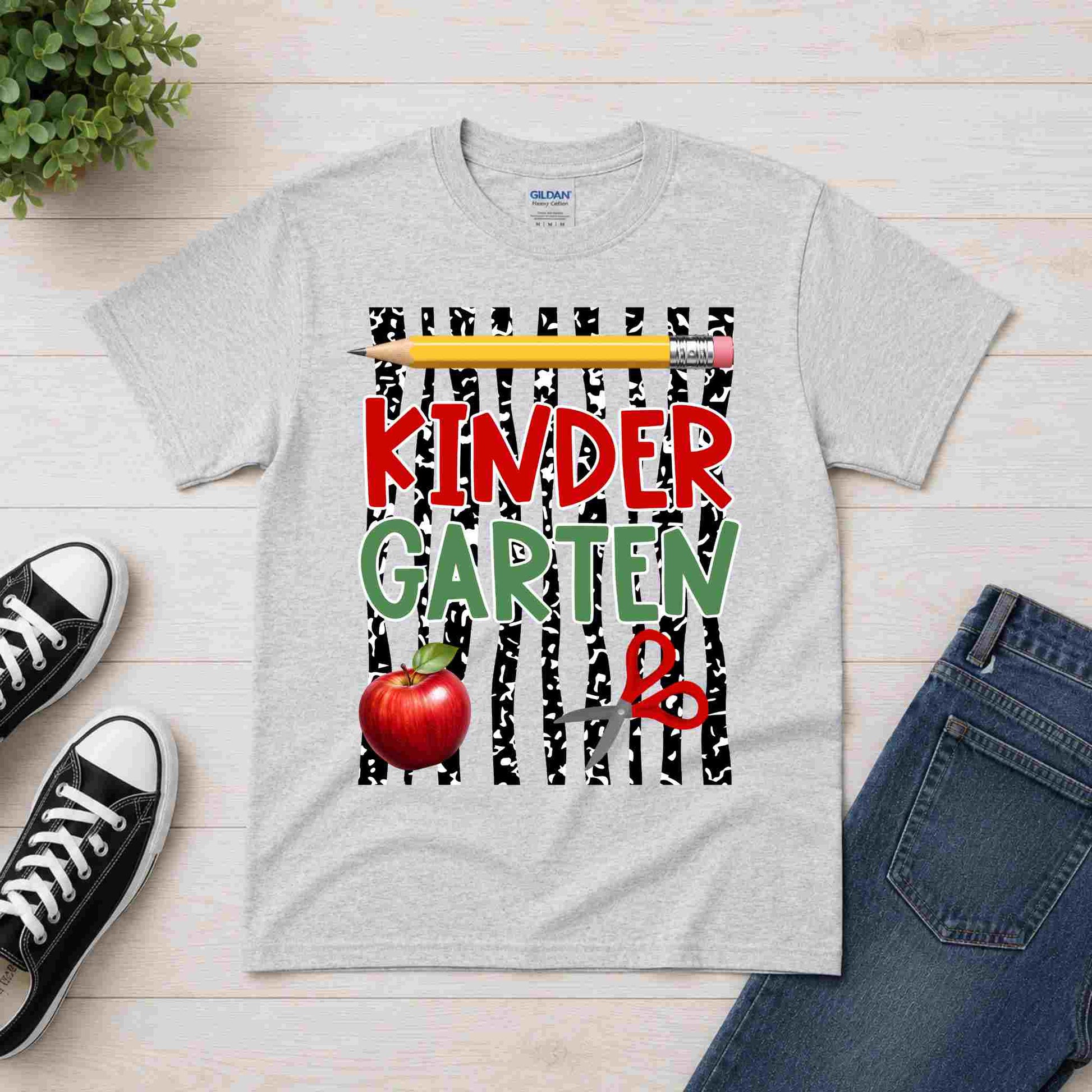 Gray t-shirt with 'Kindergarten' design on a wooden surface with shoes and jeans.