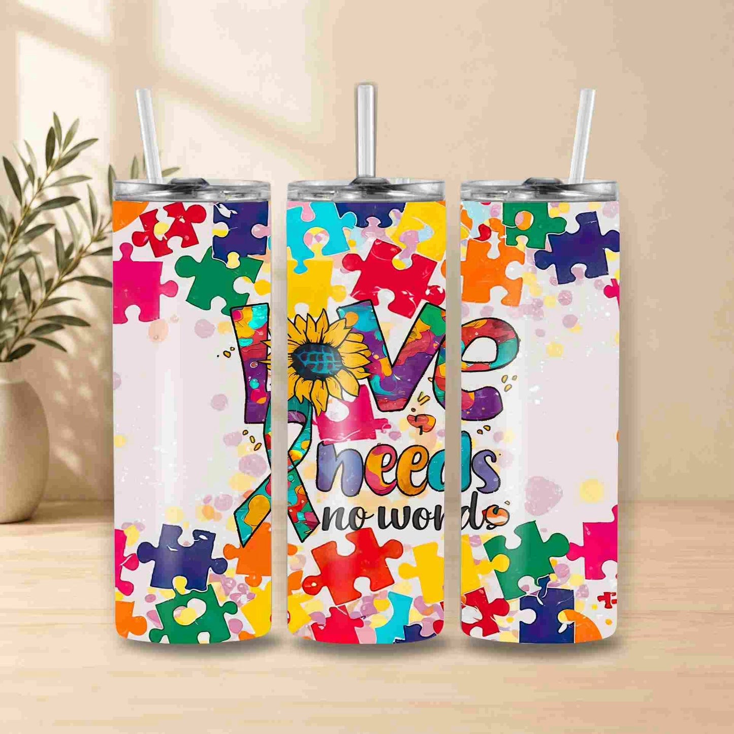 Show your support with Becca’s Banging Designs LLC’s 20oz Autism Awareness “Love Needs No Words” Tumbler, featuring puzzle piece splashes and a sunflower O. Ideal autism support gift. Plant decoration shown on the left.