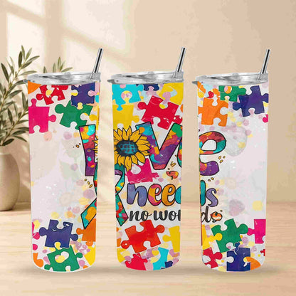 Becca's Banging Designs LLC offers the 20oz Autism Awareness Love Needs No Words Tumbler, featuring a puzzle piece sunflower and "Needs no words" phrase, shown with two other colorful cups on a light surface with plants in the background.