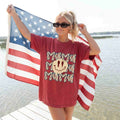 Woman holding an American flag and wearing a red 'Mummy' t-shirt by a body of water.