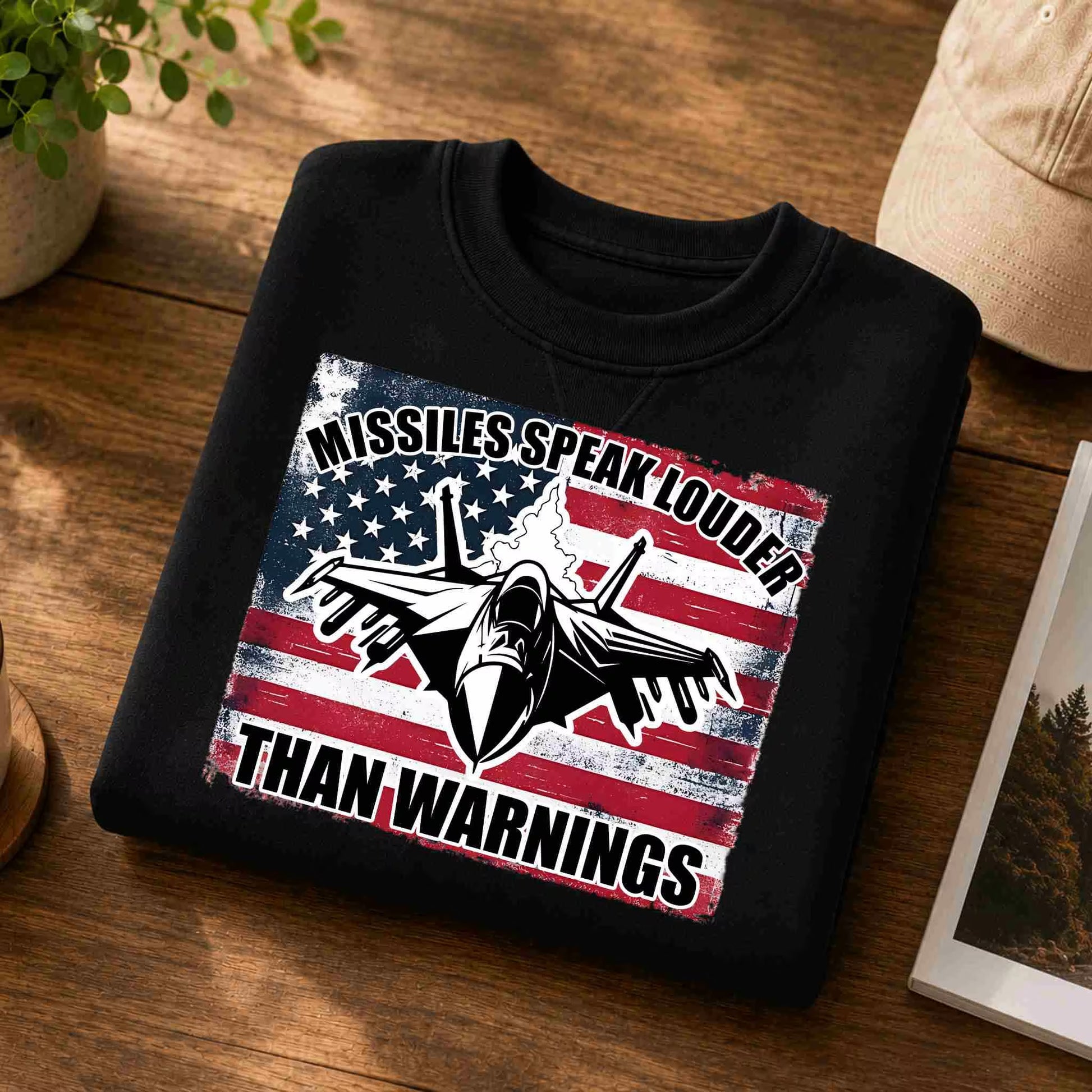 Black sweatshirt with American flag and airplane design on a wooden surface