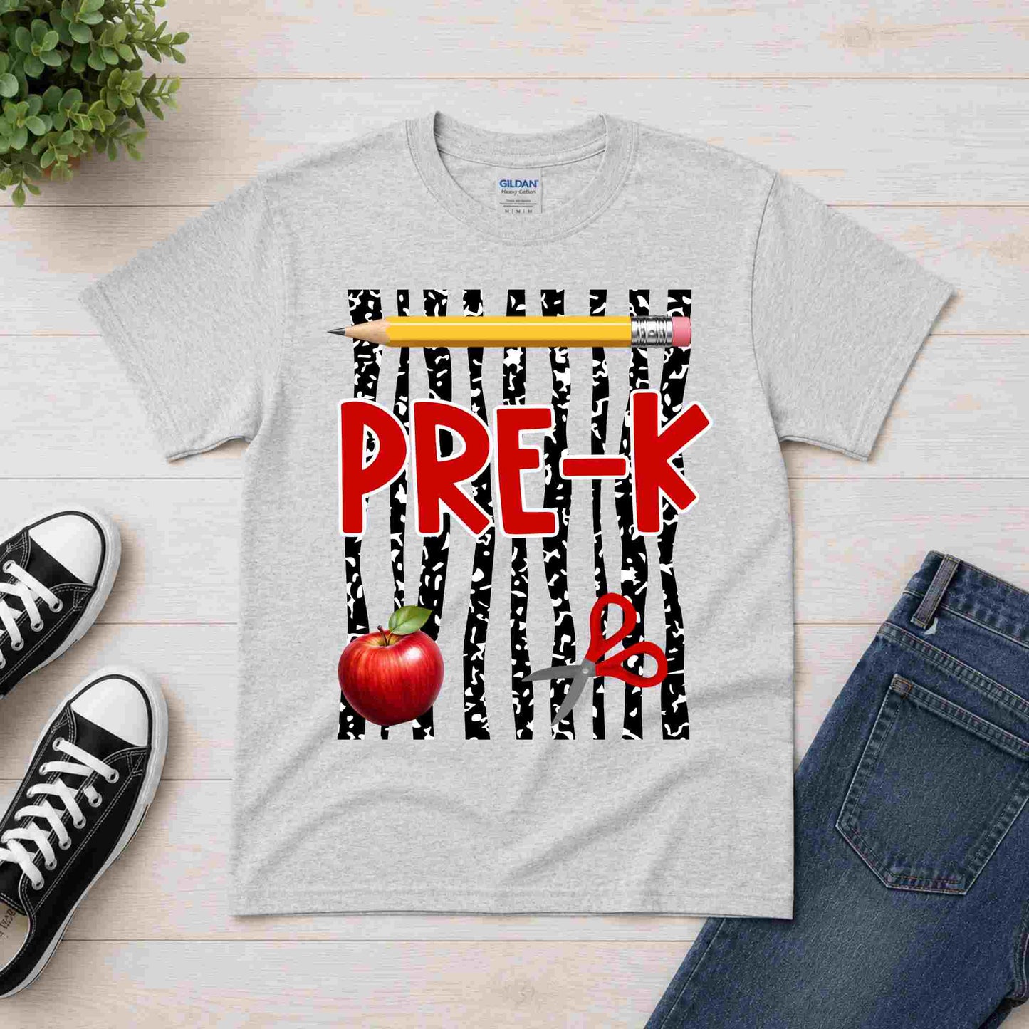 Gray t-shirt with 'PRE-K' design featuring a pencil and apple on a wooden surface with shoes and jeans.