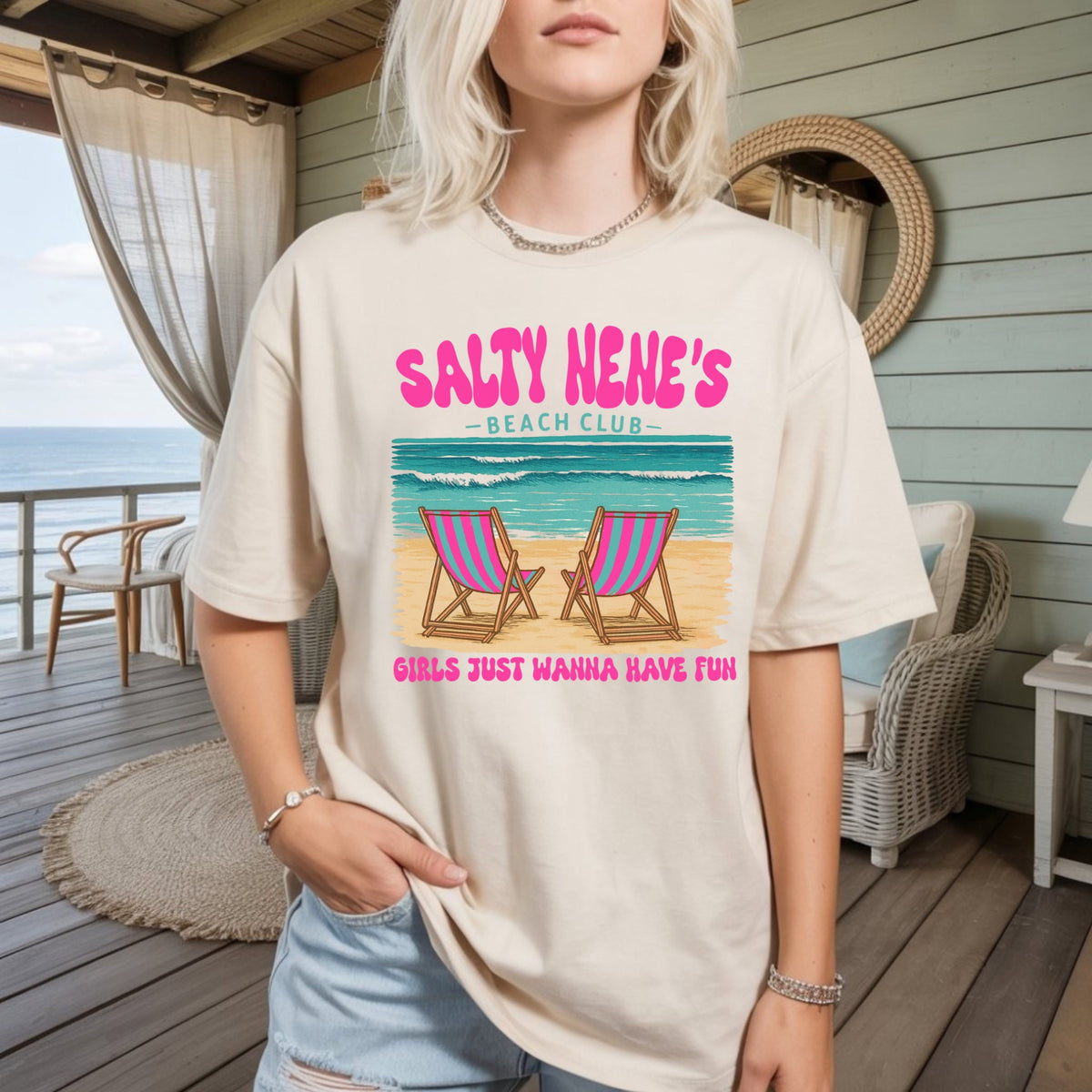 Women's beige graphic t-shirt with 'Salty Nene's Beach Club' text and lounge chair graphic
