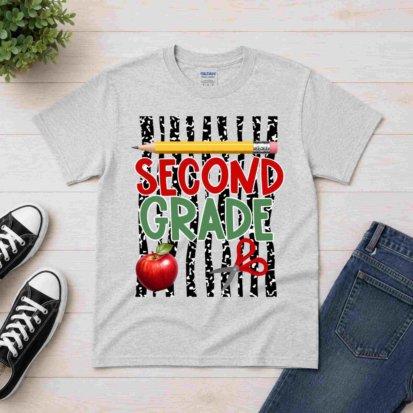 Gray t-shirt with 'Second Grade' design featuring a pencil, apple, and zebra print on a wooden surface with shoes and jeans.