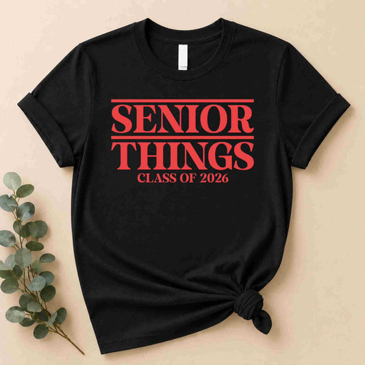 The Senior Things Shirt Class of 2026 Tee by Becca's Banging Designs LLC boasts bold red "Senior Things Class of 2026" text in a Stranger Things style—perfect as a funny senior year graduation outfit or last year vibes shirt.
