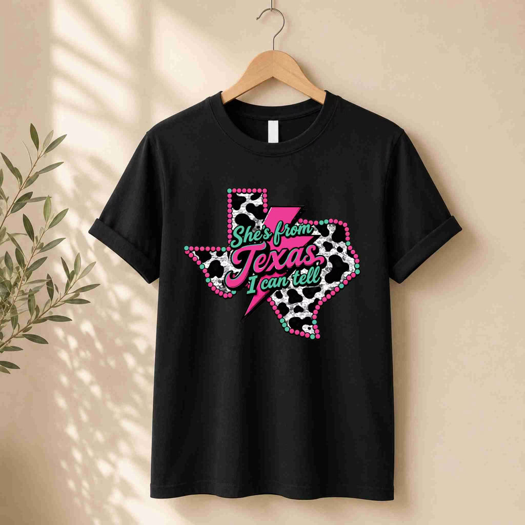 Black t-shirt with Texas design and text on a hanger against a beige wall.