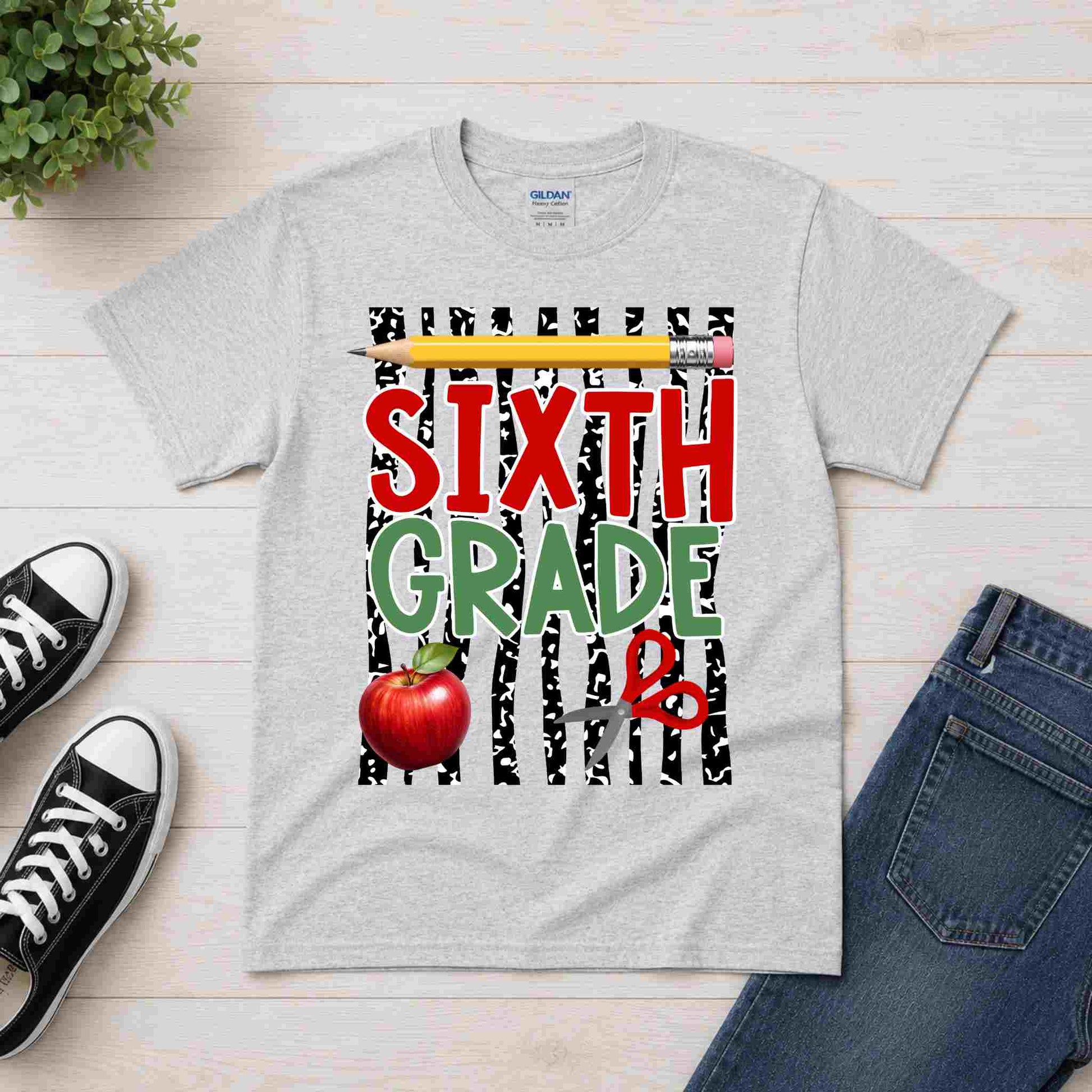 Gray t-shirt with 'Sixth Grade' design on a wooden surface with shoes and jeans.