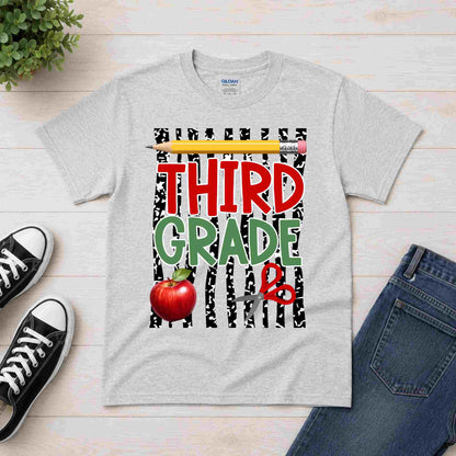 Gray t-shirt with 'Third Grade' design on a wooden surface with shoes and jeans.