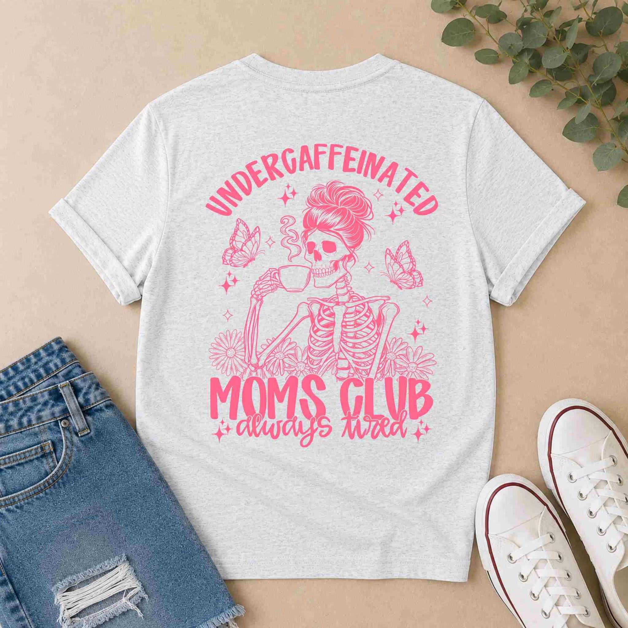 The Undercaffeinated Moms Club Shirt – Funny Tired Mom Tee by Becca's Banging Designs LLC features a light gray color with pink skeleton coffee art, flowers, and butterflies—perfect with ripped denim shorts and white sneakers for cute mom outfits.