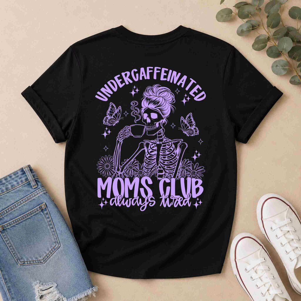 The Undercaffeinated Moms Club Shirt by Becca's Banging Designs LLC is a black tee with a purple skeleton mom, butterflies, and bold text—perfect for tired moms and cute outfits. Pair with denim shorts and sneakers for a casual look.