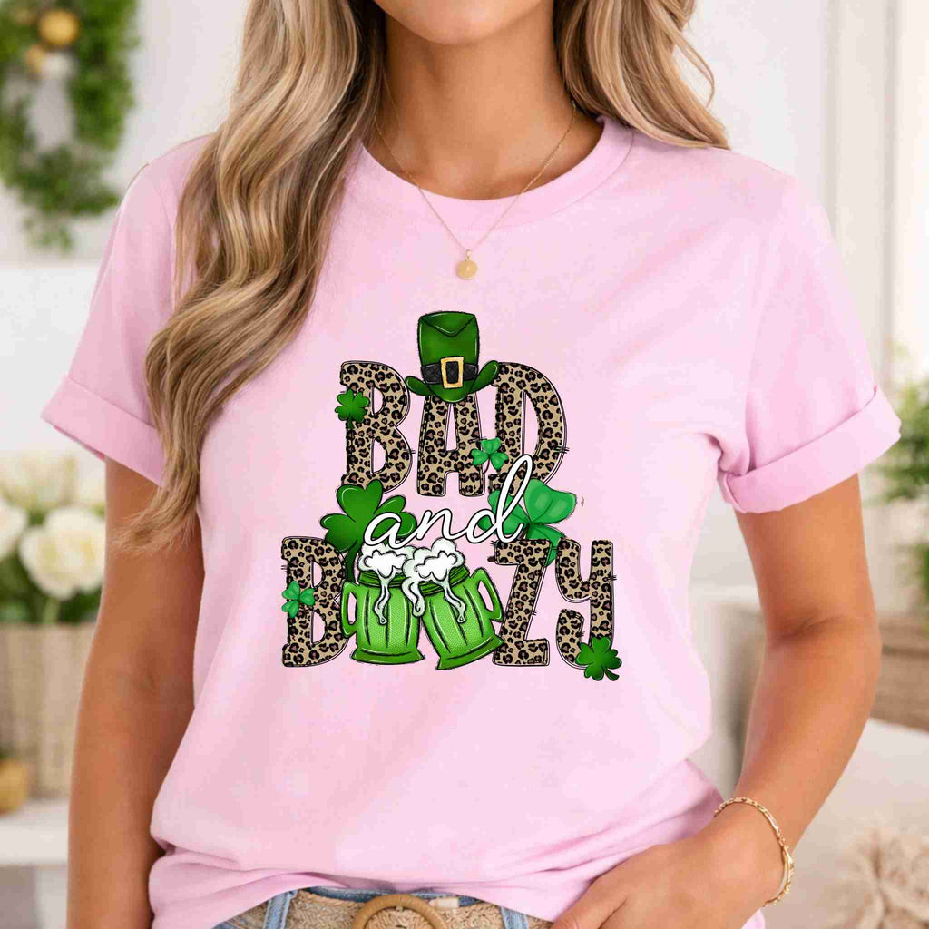 St. Patricks Day shirt featuring Bad & Boozy graphic design on a light pink tee.