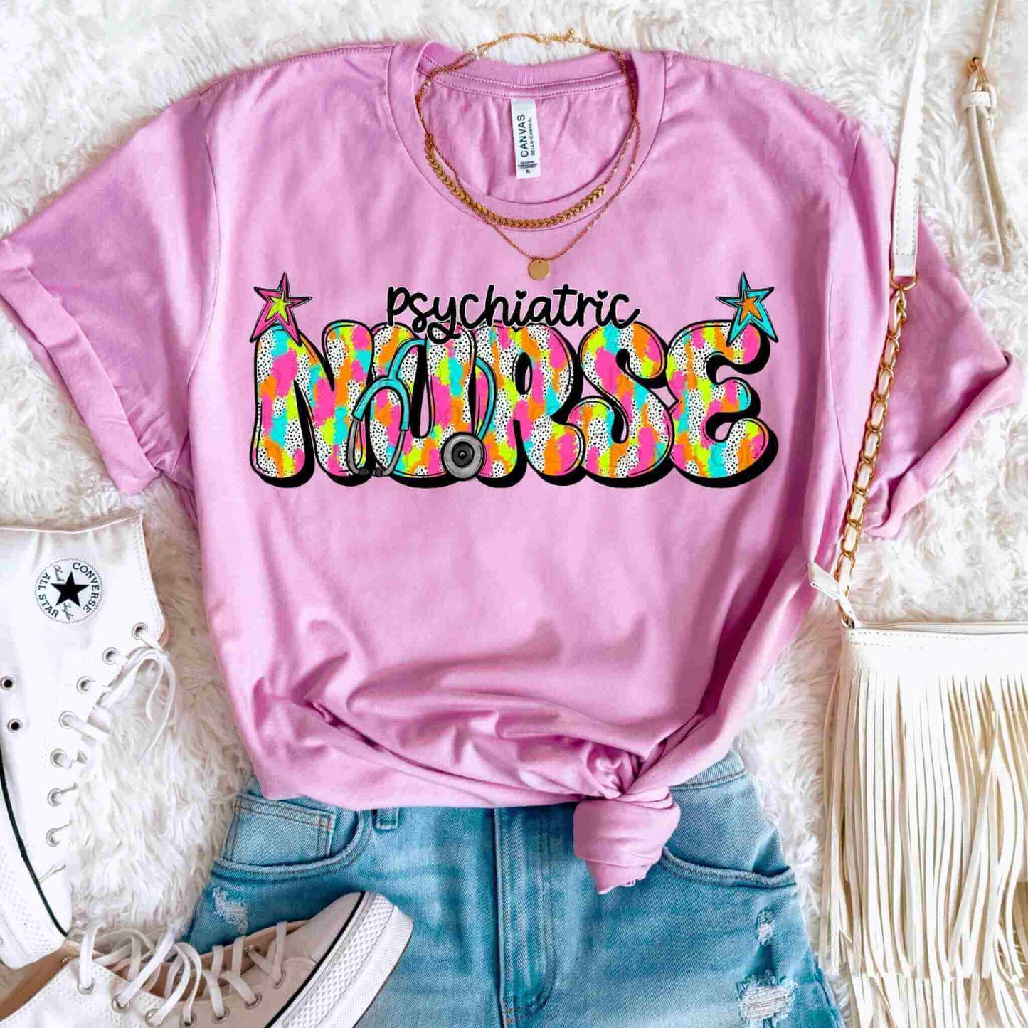 A pink women’s graphic tee from Becca's Banging Designs LLC, featuring colorful “Registered Nurse, Labor & Delivery, School Nurse” text—styled with casual accessories and perfect for nurse appreciation gifts.