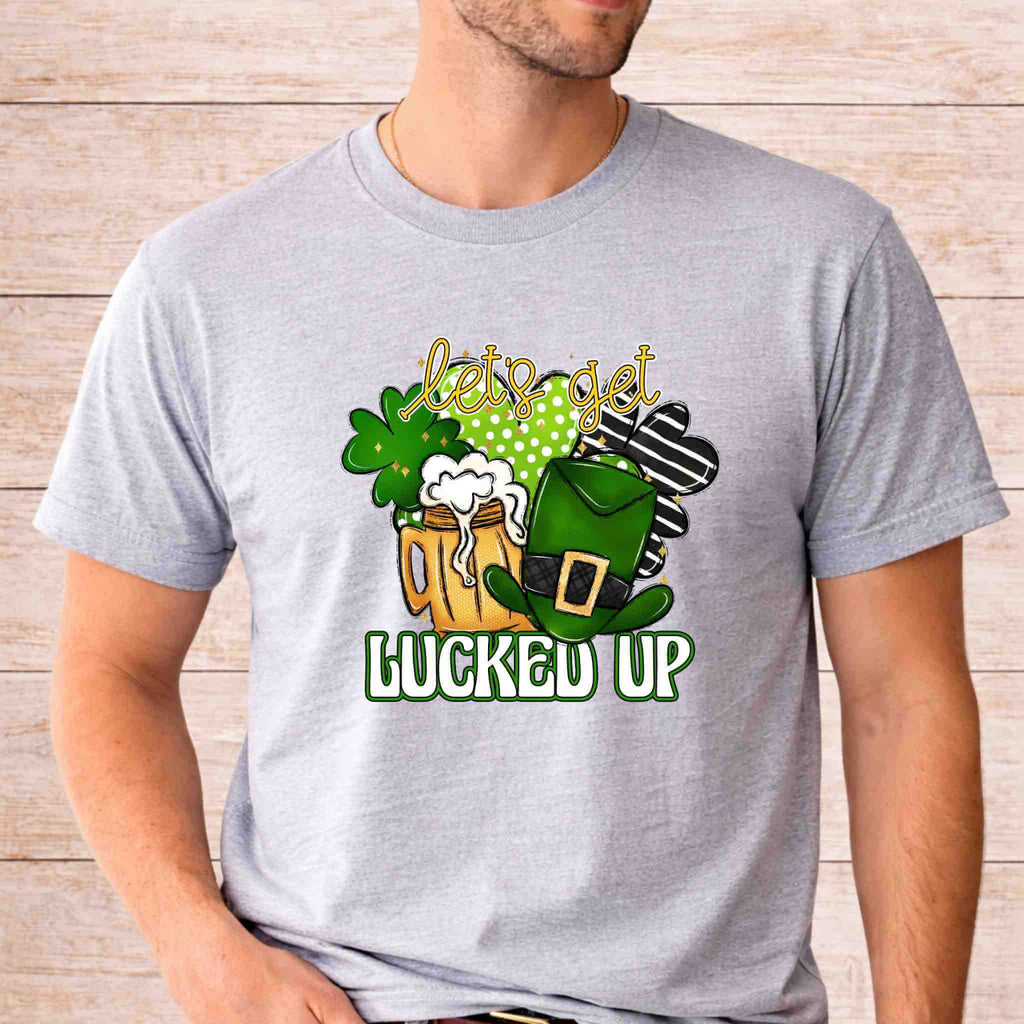 St. Patricks Day shirt featuring a fun design with shamrocks, beer mug, and leprechaun hat that says "let's get lucked up".