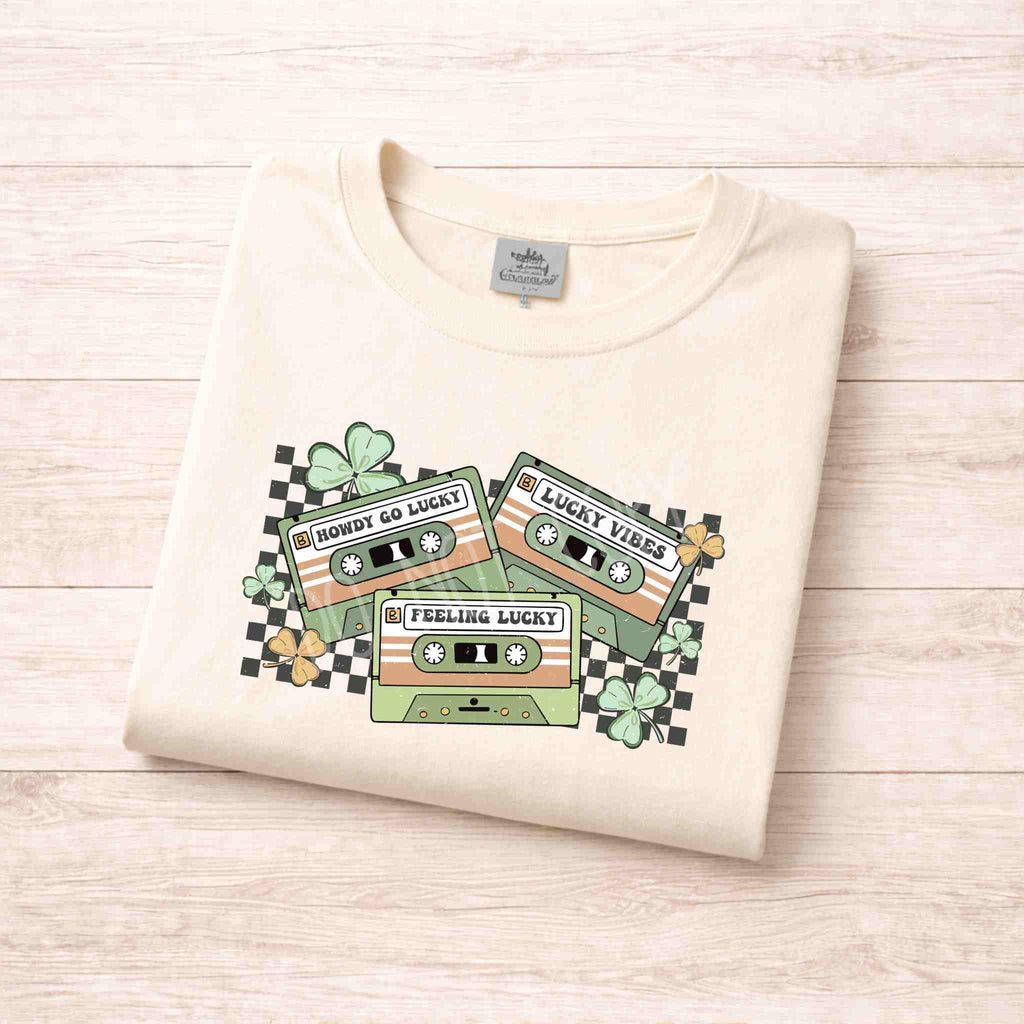 St. Patricks Day shirt featuring a retro cassette graphic with shamrocks in soft colors.