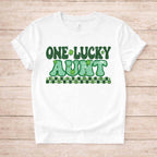 St. Patricks Day One Lucky Aunt tee with retro lettering and shamrock accents on a white background