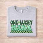 St. Patricks Day matching tee featuring green retro text 'One Lucky Nana' on a gray shirt.