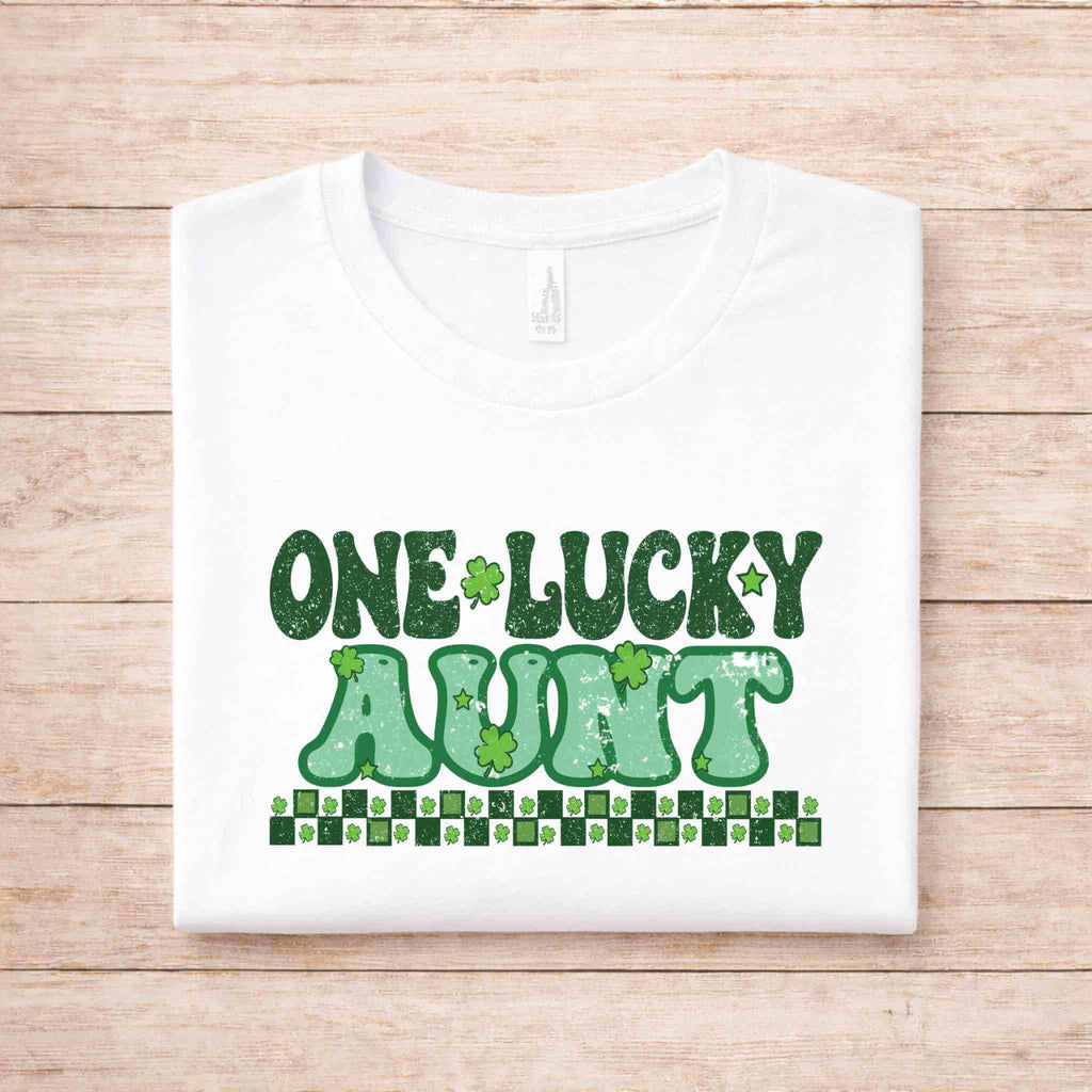 St. Patricks Day One Lucky Aunt shirt with green lettering and shamrock designs on a white background.