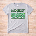 St. Patricks Day Teacher T-Shirt with One Lucky Teacher graphic and shamrocks in green on a grey tee.