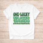 St. Patricks Day Teacher T-Shirt featuring cute shamrock graphic and bold retro lettering on a white background.